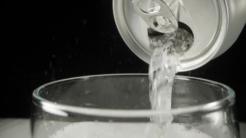 I pour soda from a jar into a glass, it bubbles and hisses, Bubbles jump up. Close-up.