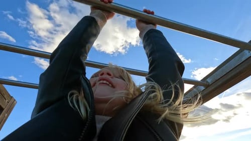 Kid is Hanging Monkey Bar at the Playground