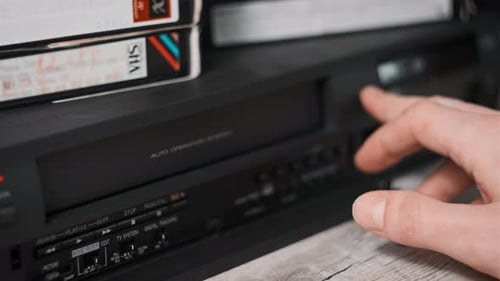 Hand Inserts VHS Tape Into VCR