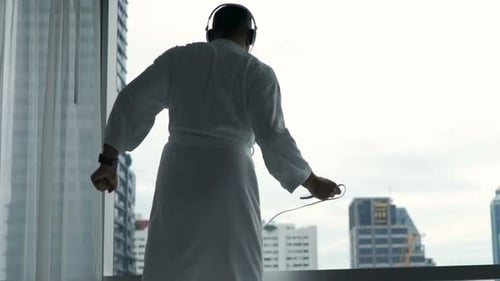 Man in robe listening to music dancing indoors