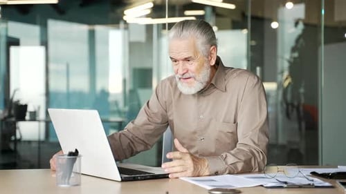 Senior Man Video Calling on Laptop in Office
