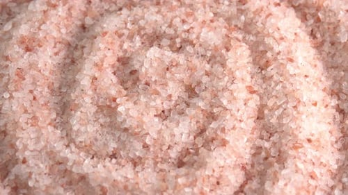 Pink himalayan salt or rock salt rotating close up spiral background side view sun light. Trace