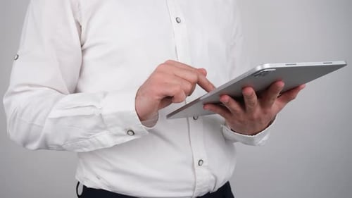 Man Interacting with Silver Tablet Indoors