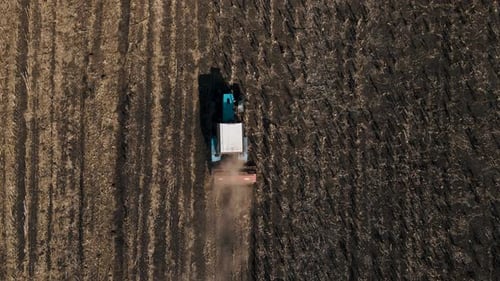 Aerial View of Agricultural Tractor Preparing Land Harrows the Soil on the Fertile Farm Fields