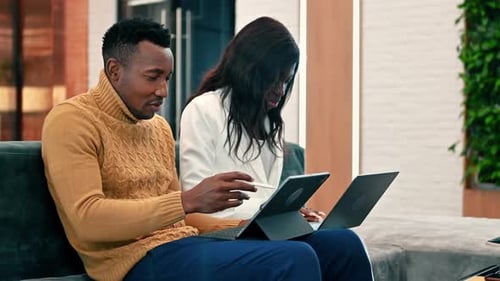 Black male and female workers in an office discussing and working using tablets. Slow motion