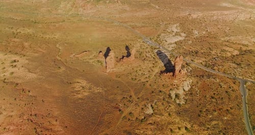 Few lonely little rocks among the deserted landscape. Highway crossing the scenery with some cars