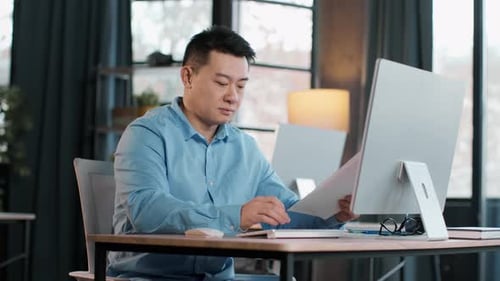 Professional Man Focused on Work at Modern Desk in WellLit Office During Daytime