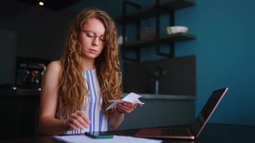 Woman Does Accounting at Desk in Kitchen