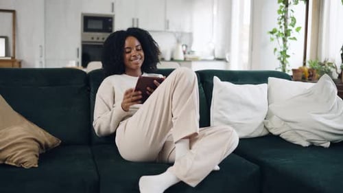 Woman Relaxing on Couch Using Tablet at Home