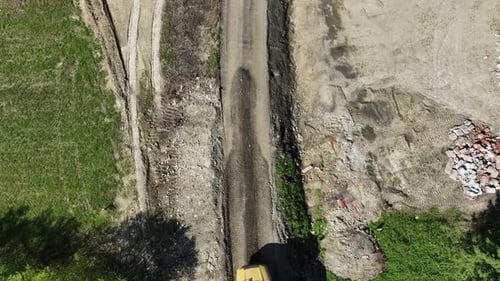 Aerial top down view on dump truck transporting load of soil on construction site