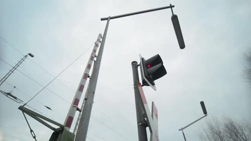 Portão de travessia ferroviária e sinal com semáforo vermelho em um dia nublado
