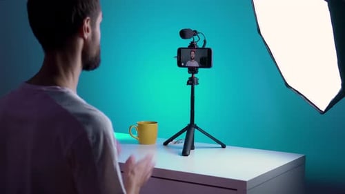A Young Blogger Records a Video with Himself on His Phone in His Studio