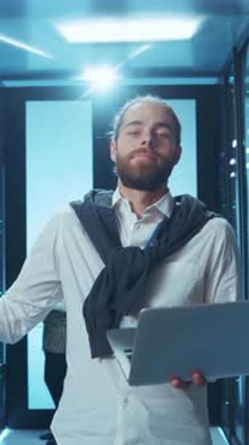 A Professional Man is Actively Working in a Data Center While Using His Laptop Computer