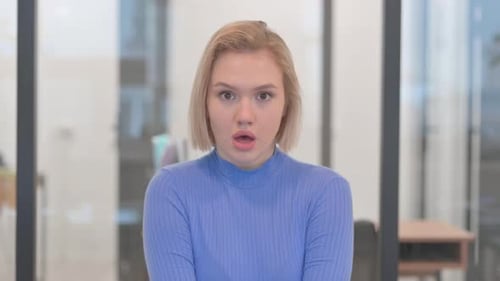 Young Woman Looking Surprised in Office Setting