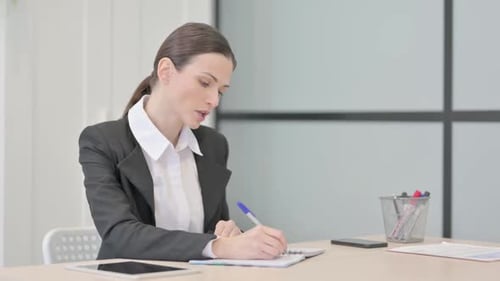 Businesswoman Writing while Sitting in Office