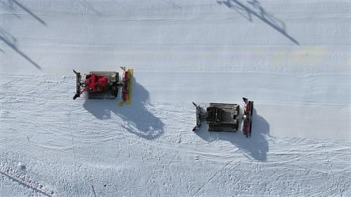 Dameur et déneigeur travaillant sur une piste de ski, vue aérienne