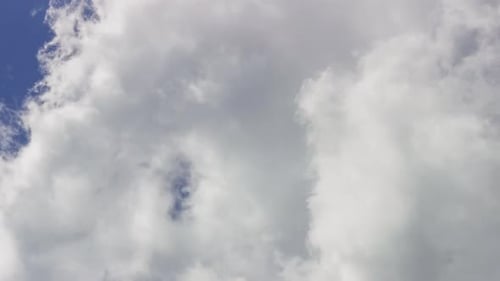 Fluffy Clouds Slowly Drifting Across Blue Sky