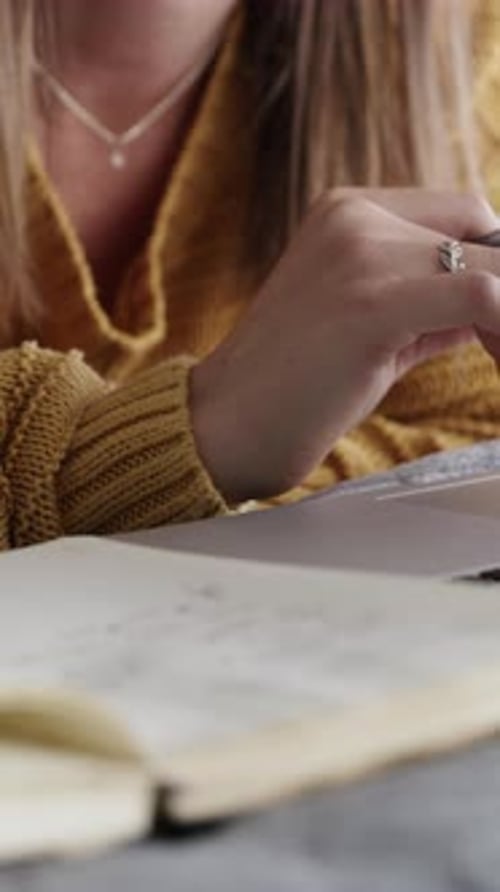 Woman Writes in Notebook with Laptop Nearby