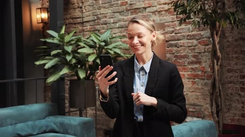 Smiling Business Woman Having Video Call on Smartphone in a Modern Office Room