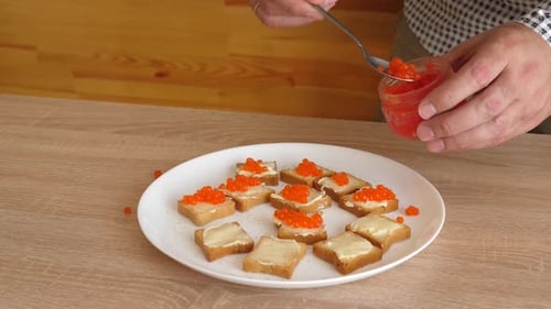 Person Making Caviar Sandwiches on a White Plate
