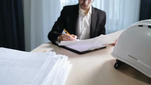 The engineer works with paper documentation in the office. Calculation and planning of drawings.