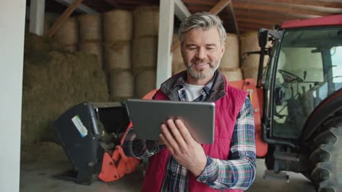 Man Holding Tablet Device in Barnyard Setting