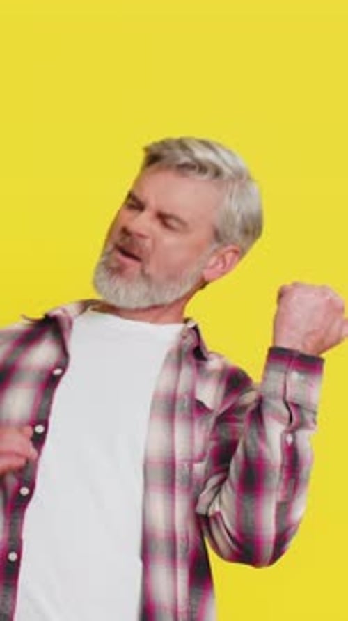 Energetic Man Dancing on Yellow Background in Studio