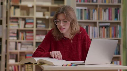 Jeune étudiante effectuant des recherches dans une bibliothèque à l'aide d'un ordinateur portable