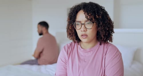 Upset Woman with Man Sitting on Bed