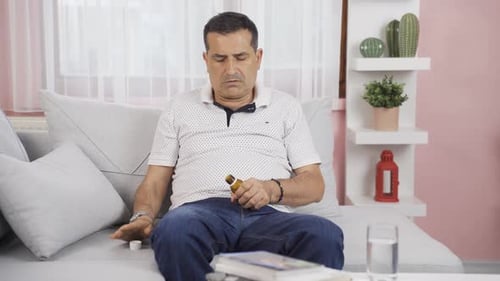 Man Taking Pills on Sofa Indoors