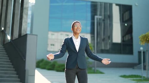 happy cheerful african american business woman in suit joyfull walks in urban city street.