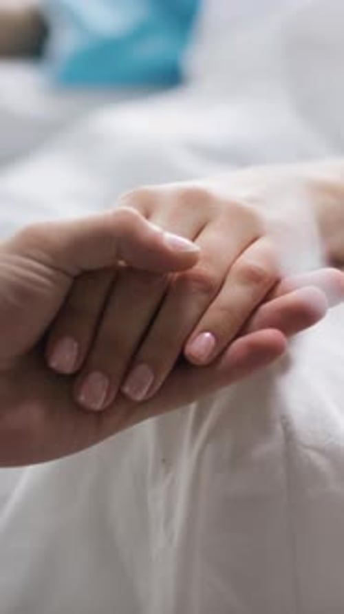 Anonymer Mann hält Hand einer kranken Frau im Krankenhaus