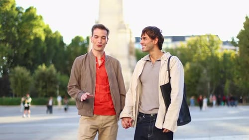 Happy Gay Couple Holding Hands While Walking and Talking in a City Park