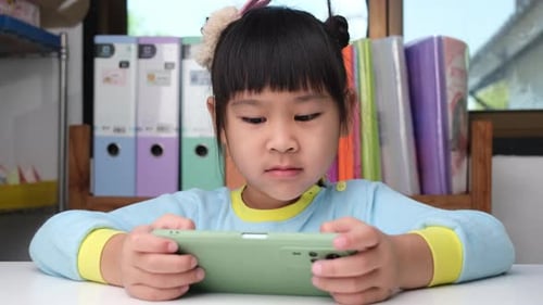 Little Girl Playing on a Smartphone Indoors