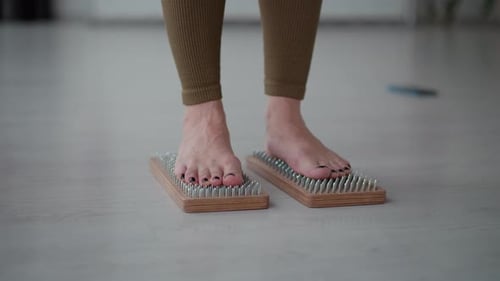 Leg View Yoga-Spezialist steht auf hölzernen Nagelbrettern und demonstriert Gleichgewicht