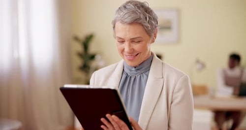 Senior Woman Smiling While Using a Tablet at Work