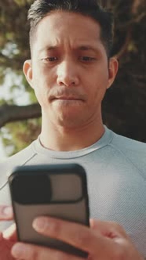 Young man sitting on a park bench uses a mobile phone