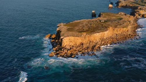 Aerial Establishing Shot of Small Peninsula at Sunset and Sea Waves Portugal