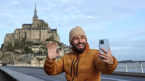 Man Video Calls with Mont Saint Michel Background
