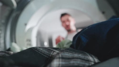 Man Loading Dirty Laundry into Washing Machine