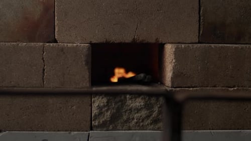 A blacksmith puts a firestarter into a forge to start working in their workshop