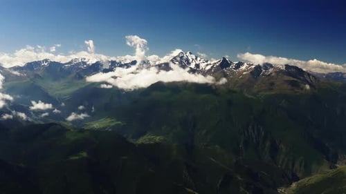 Snowy Peaks Tower Over Lush Valleys Partially Obscured By Clouds Majestic SnowCapped Peaks Above