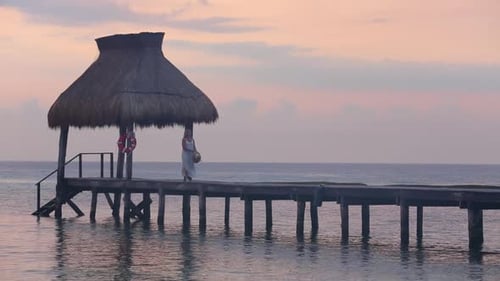 Woman Walks Along Pier at Tropical Resort Beach