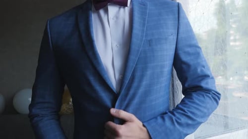 Groom adjusts jacket preparing for wedding day