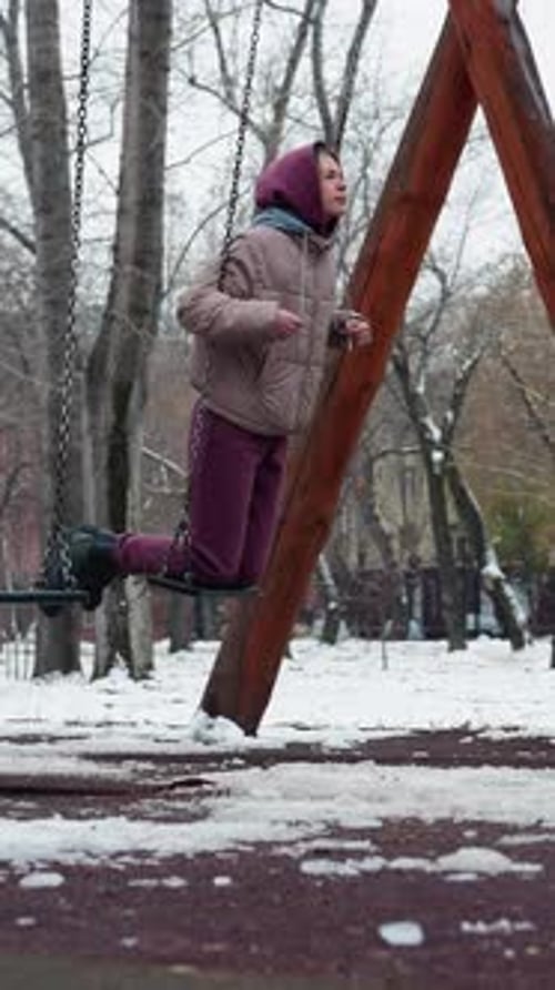 Winter Swinging in Snowy Park with Bare Trees and Cold Weather