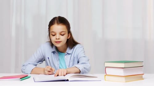 Education, People, Children And Learning Concept - Happy School Girl With Books Writing To Notebo...