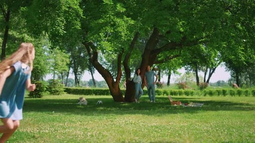 Pretty Girl Escaping Brother on Green Lawn Enjoying Family Picnic. Playful Sister