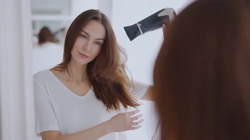 Young Woman Styling Hair with Blow Dryer at Home