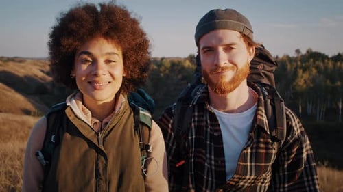 Close Up Portrait of Young Mixed Race Couple with Nordic Walking Poles on Sunset Hill Looking in