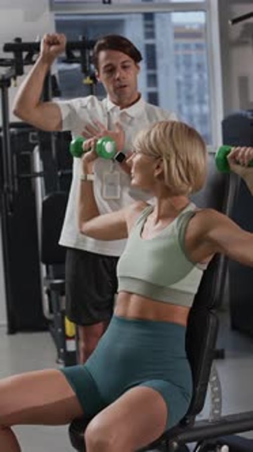 Coach Guiding Woman Lifting Hand Weights during Individual Training in Gym